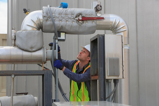Industrial engineer reading a transducer display on insulated high pressure pipe in a power plant