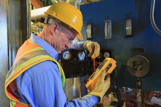 Engineer in electric power plant using a voltmeter to verify sensor readings