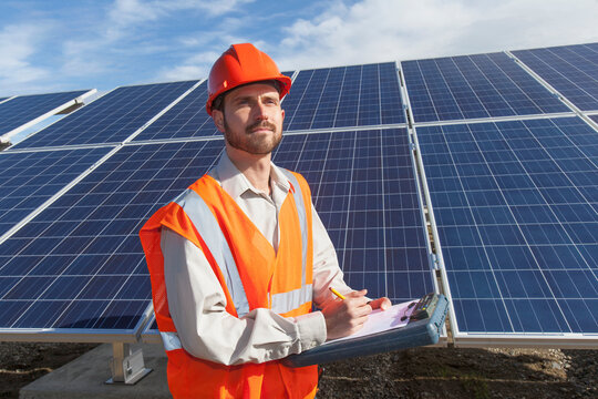 Power engineer taking notes at solar photovoltaic array