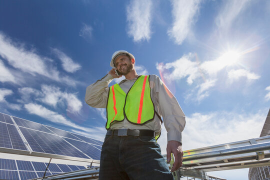 Power engineer talking on cell phone in front of solar photovoltaic array