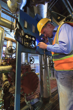 Engineer in electric power plant reviewing sensor readings with voltmeter probe