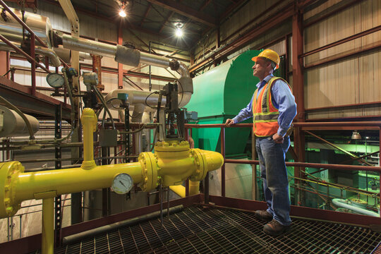 Engineer in electric power plant inspecting condenser room piping