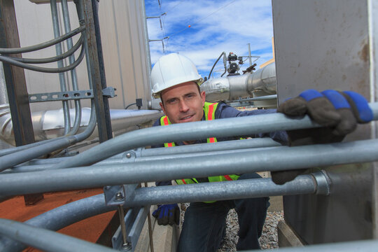 Industrial engineer examining electrical conduit at fuel tank at a power plant