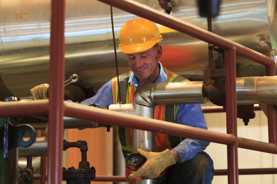 Engineer in electric power plant inspecting manual valve in condenser room piping