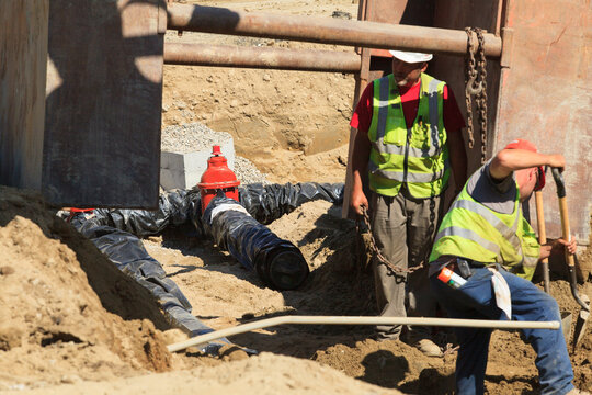 Construction engineers preparing trench for trench shield installation at construction site