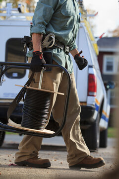 Tradesman holding cable for internet installation with work truck behind him