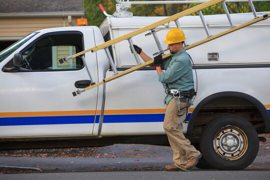 Lineman taking ladder from truck at site