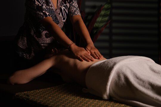Thai Therapist performing full back massage with hands applying pressure on client for wellness