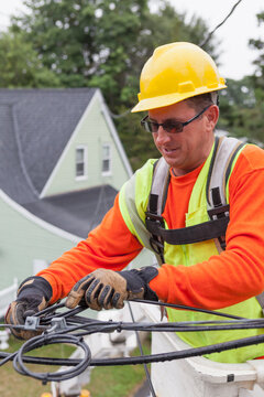 Cable lineman securing cable from house in a bucket truck