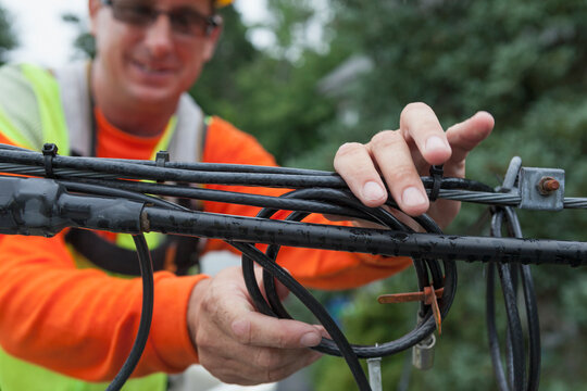 Cable lineman storing old cable to guy-wire from a bucket truck