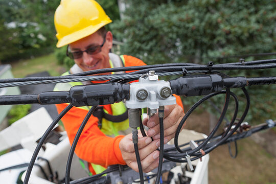 Cable lineman attaching a line filter from a bucket truck