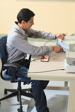 Engineering student adjusting oscilloscope to measure prototyping breadboard for an electronics lab