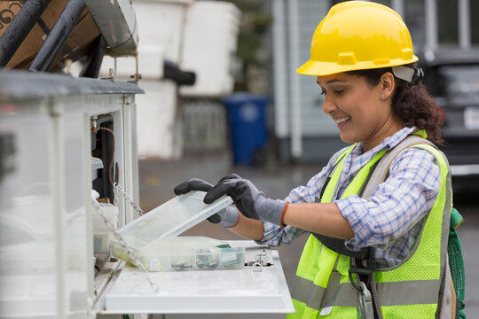 Hispanic female utility worker with box of cable amplifiers at site