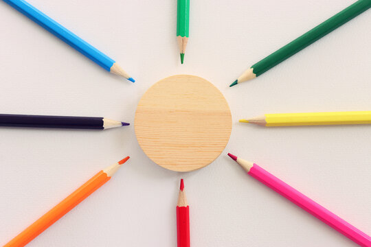 Colorful pencils and wooden circle