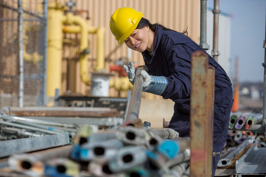 Female power engineer sorting through scaffolding at power plant