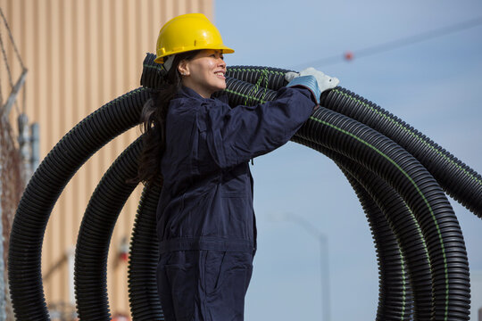Female power engineer moving flexible drainpipes