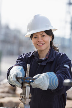 Female power engineer adjusting water valves at power plant