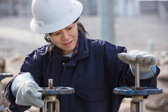 Female power engineer adjusting water valves at power plant