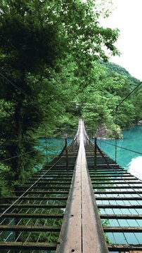 静岡県川根本町の寸又峡にある名所「夢の吊り橋」の上からエメラルドグリーンの湖面を見下ろす風景-縦動画