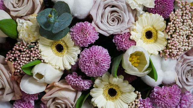 Top-down view of an exquisite spring flower bouquet with purple chrysanthemums, white gerbera daisies, pastel roses, and cotton flowers. Full frame floral background with selective focus on fresh blos