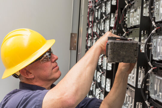 Engineer connecting energy storage batteries for back up power to an electric power plant