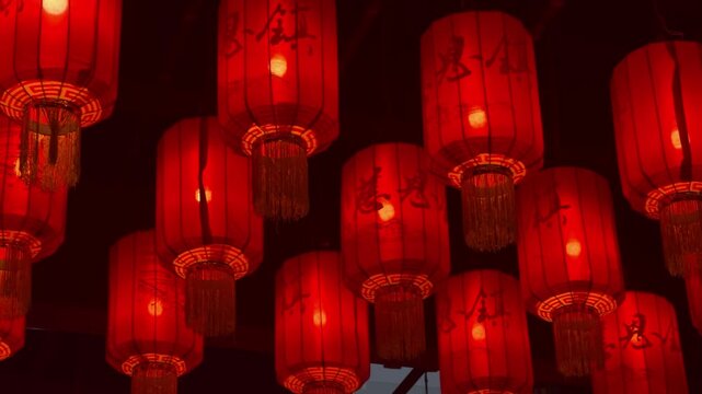 Traditional red chinese lanterns hanging in row at night. Glowing paper lamp for lunar China new year celebration. Asian culture decoration for festival atmosphere and street lighting background.