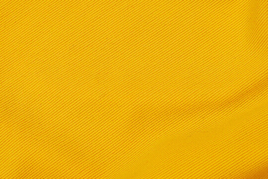 Bright yellow fabric texture shown in close up, revealing woven patterns and smooth lines under natural light in daytime