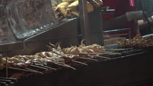 Slow-motion footage of squid being grilled as street food in Bangkok, Thailand.