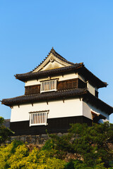 Fototapeta premium Historic Japanese castle turret building standing against a clear blue sky low angle view