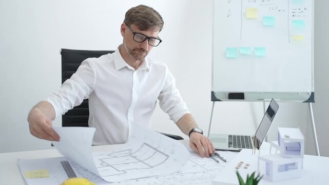 Architect drawing building plans on blueprints using a compass, creating a new construction project design, working on engineering and drafting tasks in an office