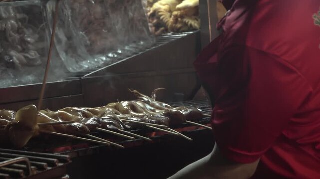 Slow-motion footage of squid being grilled as street food in Bangkok, Thailand.