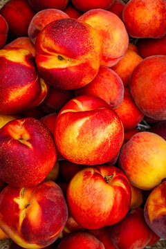 Fresh peaches stacked in a basket at a farmers market in summer sunlight