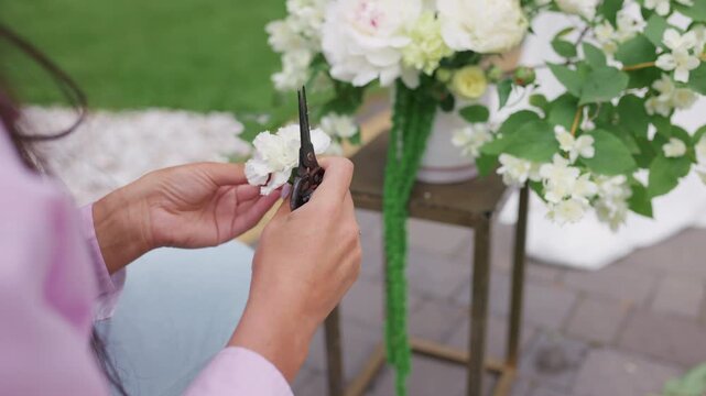 Close-up of florist hands trimming a fresh white flower with pruner outdoors