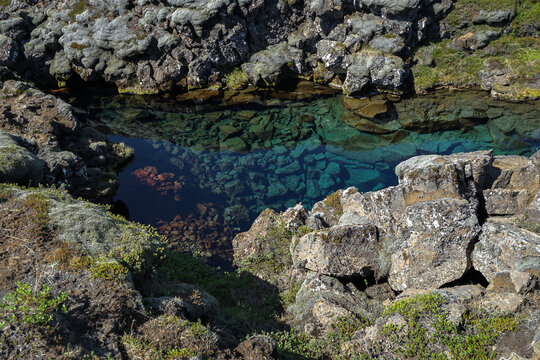 Clear turquoise water pool surrounded by moss-covered rocks in a natural rocky landscape,Silfra Fissure,ICELAND