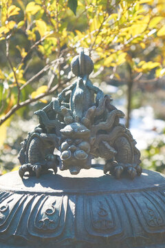 Close up of a bronze dragon sculpture on top of a traditional Japanese Buddhist incense burner