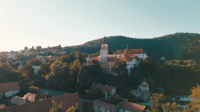 Discover the majestic Sazava Monastery nestled in the lush landscape of Prague, Czechia. Enjoy views of the surrounding hills, homes, and the peaceful atmosphere.