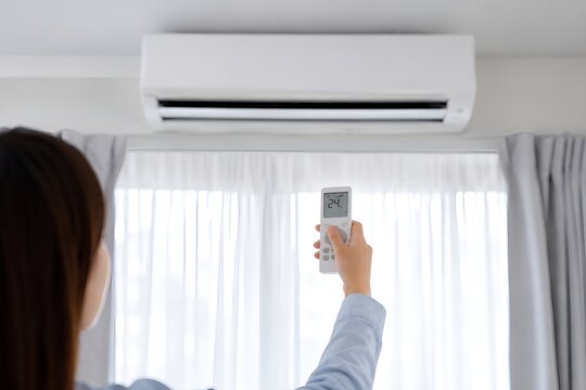 Woman using a remote control to set the air conditioner to 24 degrees Celsius