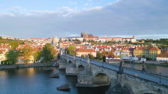 Witness the beauty of Charles Bridge and Prague Castle as the morning sun illuminates the historic buildings and the serene Vltava River flows below. Discover the charm of Czechia.