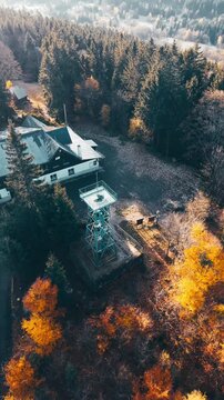 Experience stunning aerial views of the Slovanka lookout tower nestled in the Jizera Mountains. Enjoy the vibrant autumn foliage and serene forest surroundings in this beautiful region.