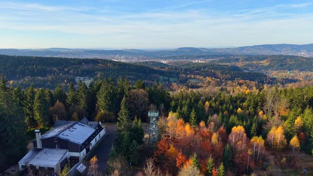 Explore the stunning views from Slovanka lookout tower in the Jizera Mountains during autumn. Experience vibrant colors and breathtaking landscapes in the forested area.