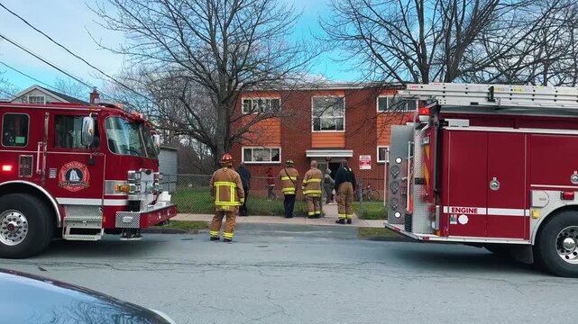 Fire truck and crew attend an emergency call in downtown Halifax Nova Scotia. Firefighters work near an apartment building on a sunny day