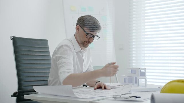 Architect designing residential building model in office, creating detailed blueprints and plans for urban development, focusing on construction project planning and creative architectural solutions