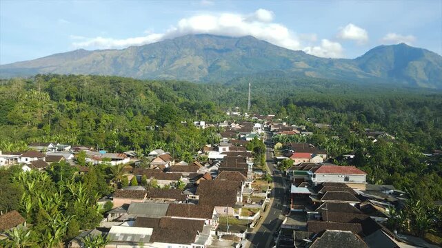 A 4K aerial view of a beautiful village beneath the majestic peak of Mount Arjuna.