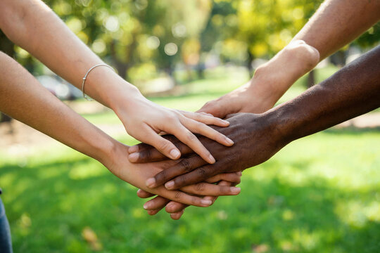 Diverse group of hands stacked together symbolizing unity and teamwork outdoors