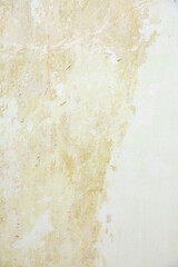 Fototapeta premium A textured wall with a light beige and cream color palette. The surface shows signs of wear and age, with subtle variations in tone and texture.