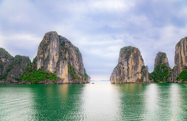 Obraz premium Beautiful tropical view of Halong bay with turquoise sea, rocky cliffs, and lush green landscape in Vietnam.