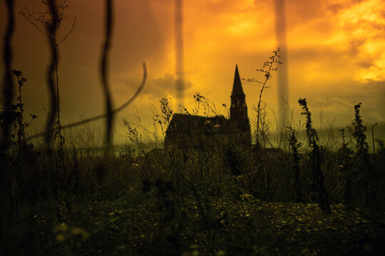 Silhouette of an abandoned church in a ghost town under a dramatic orange sky