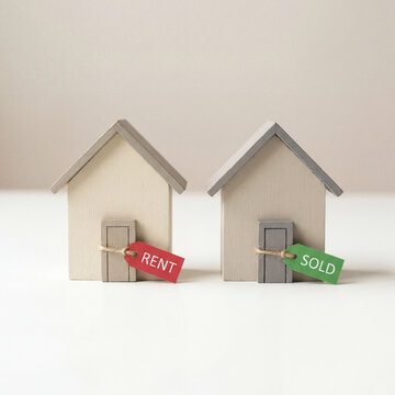 Two miniature houses with rent and sold sign flags real estate concept