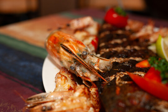 Grilled whole fish with prawns and vegetables on restaurant serving platter