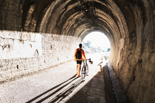 A cyclist walks into the tunnel light pushing his bike during a relaxed ride